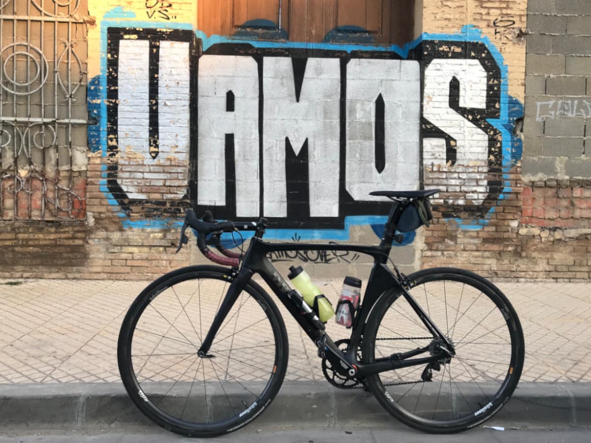 Spanish word "Vamos" spraypainted on brick wall behind bicycle.