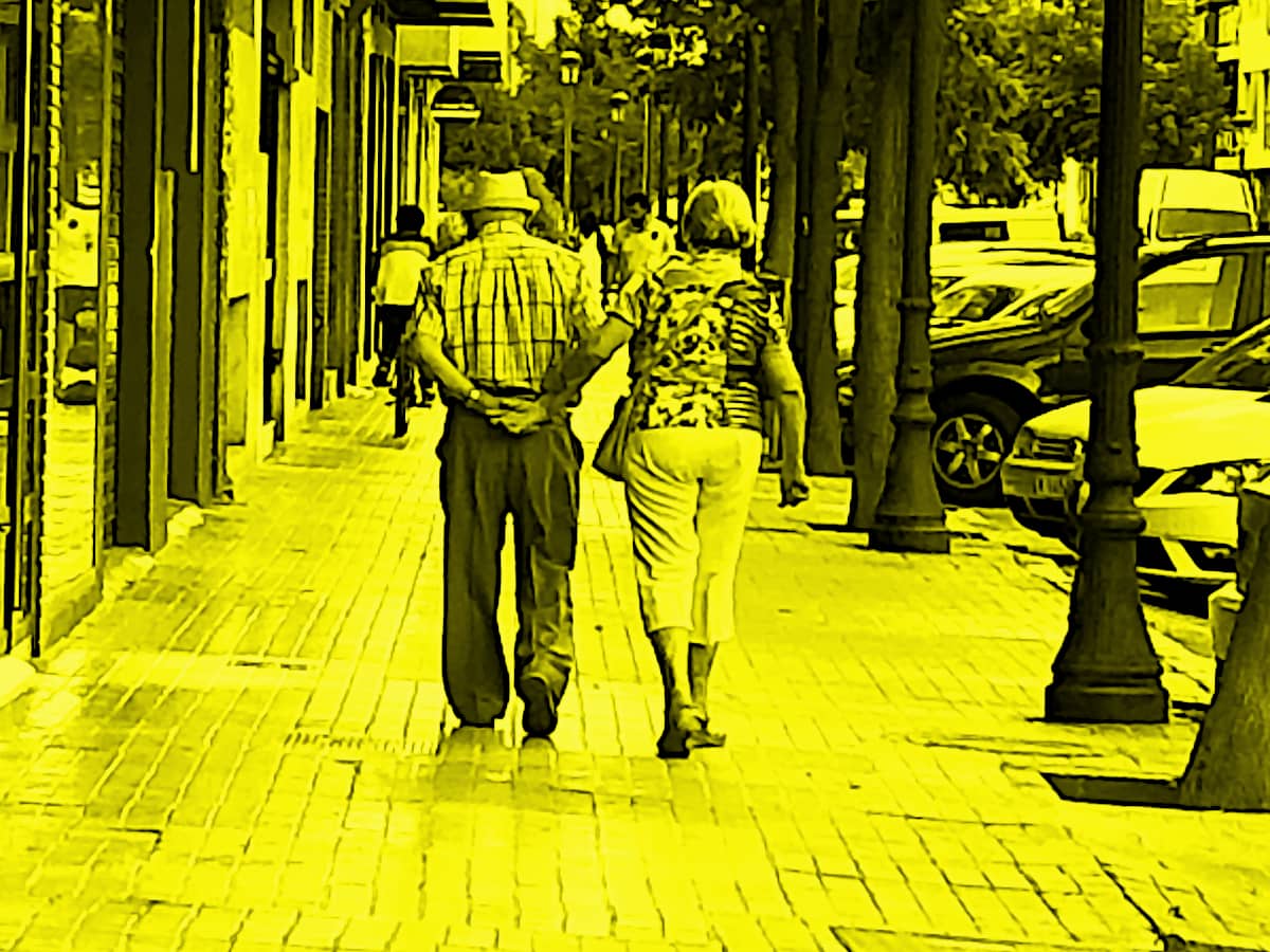 Elderly couple walking down the street with the pictured tinted in yellow.