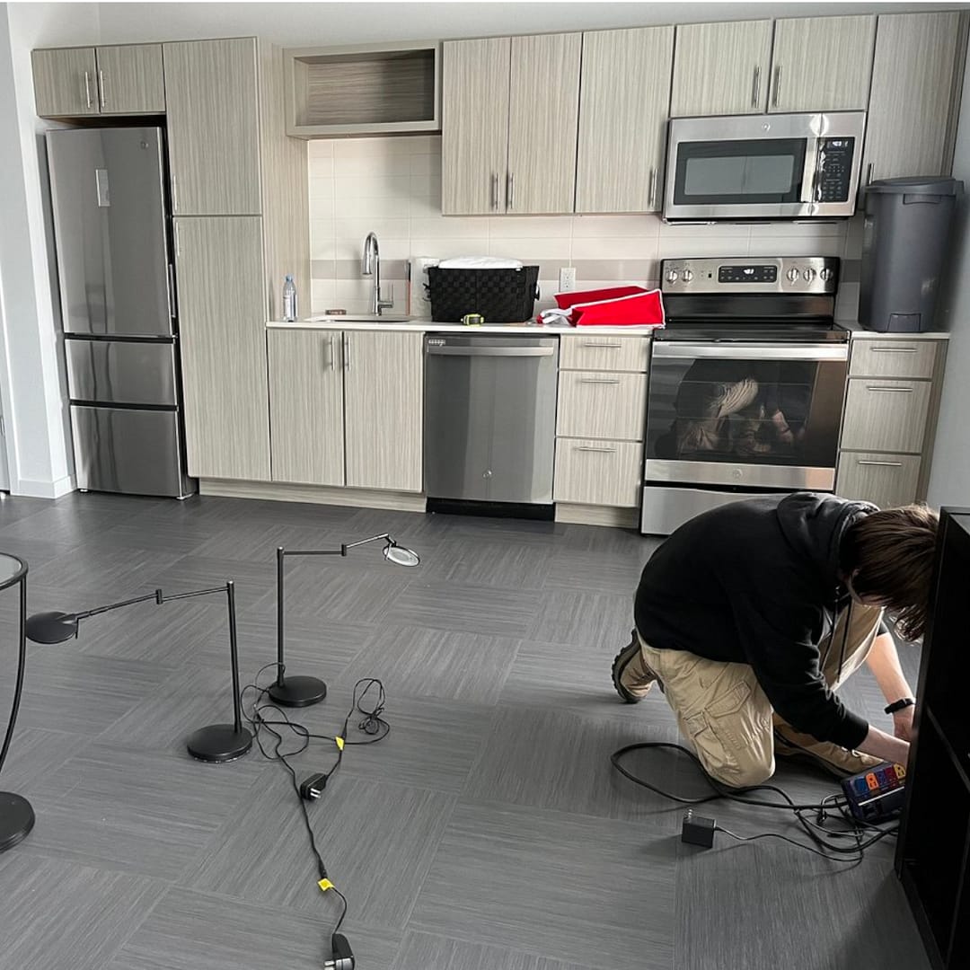 A fairly empty room with wires from a computer setup on the floor.