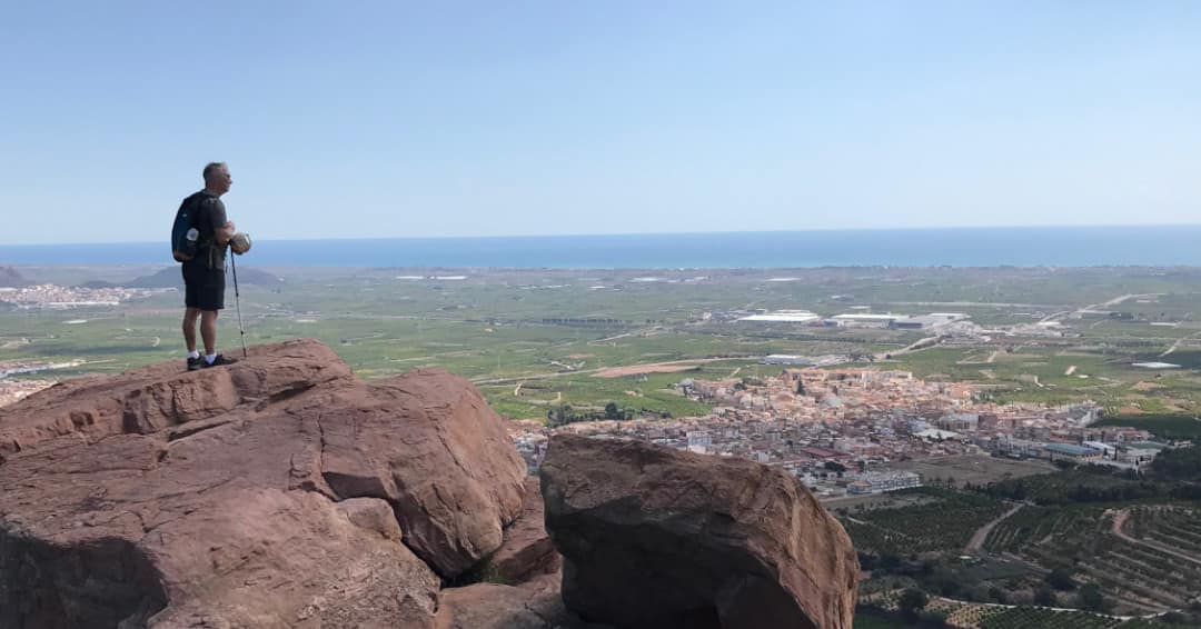 Hiker looking from an outlook towards the distant sea.