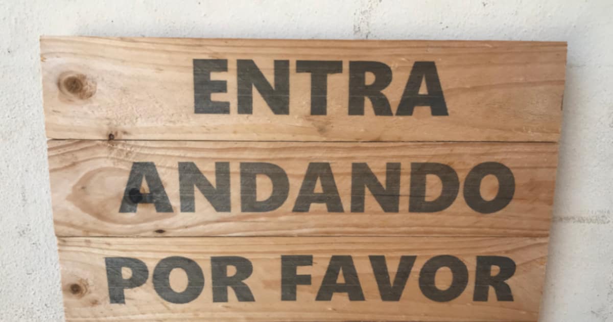 Sign with words: Entra Andando Por Favor, which means "Enter walking, please."