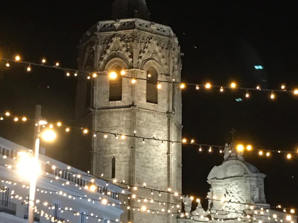 Strings of Christmas lights hang in front of a bell tower in Valencia, Spain.