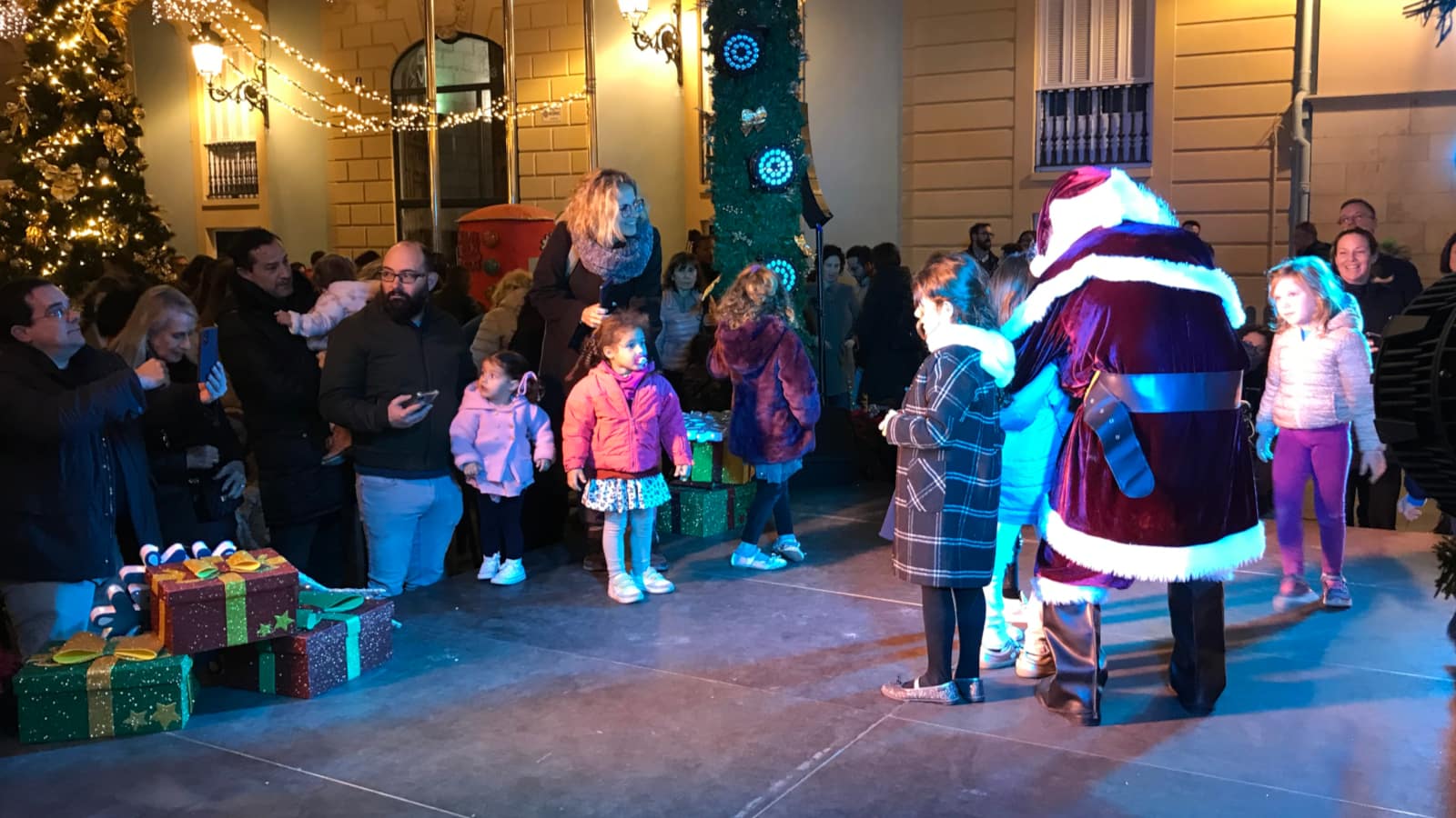 A person dressed in a Santa Claus costume stands with children for a photograph.