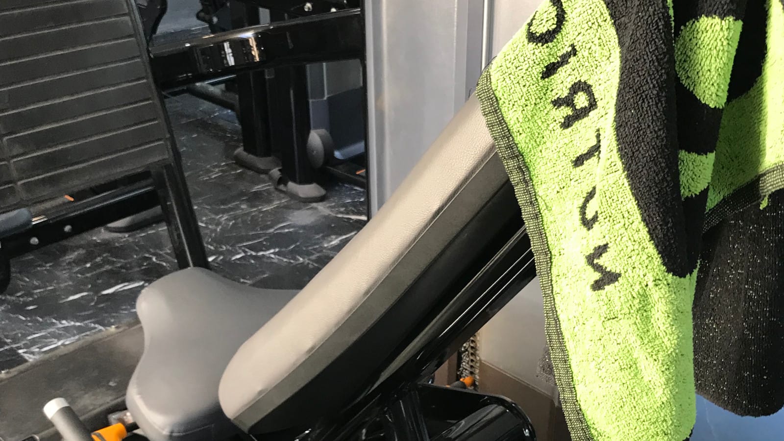Towel draped over seat of legpress machine.
