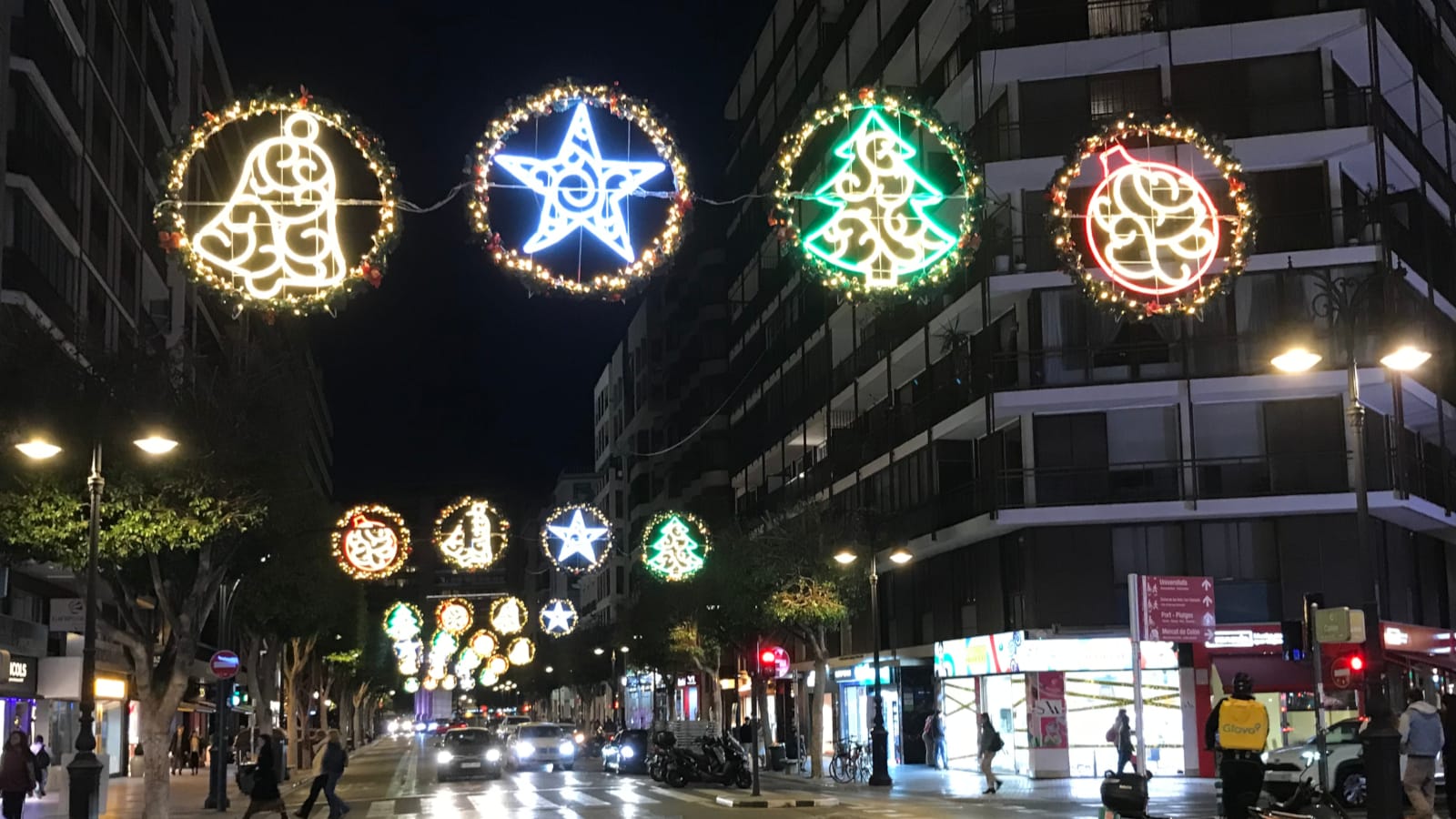 A street-level view showing trees, stars, and other shapes outlined by lights.