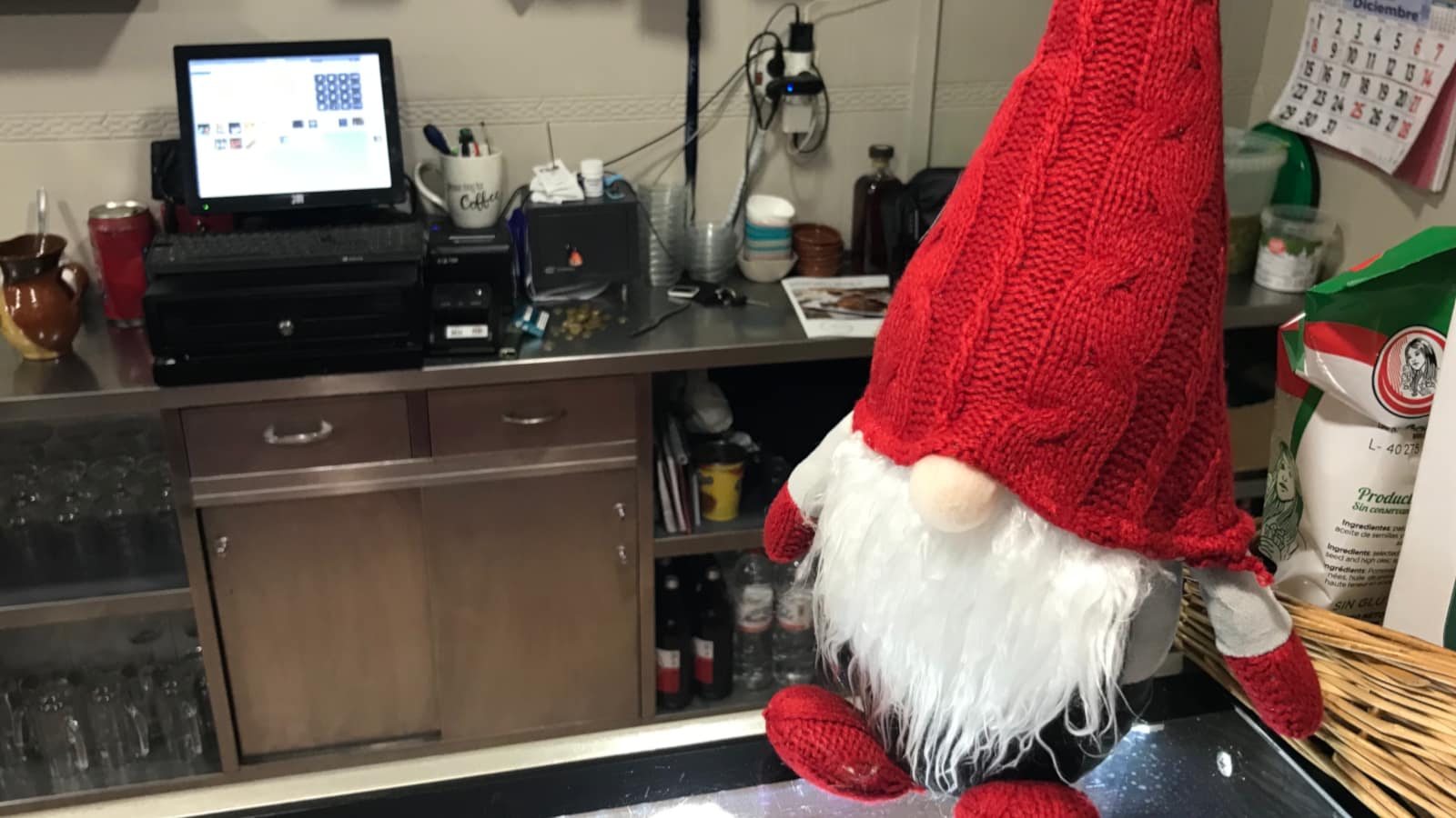 A figurine of a Christmas elf placed on a bar in front of the cash register.