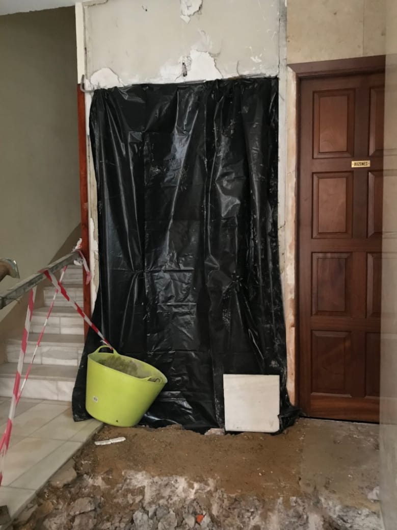 A tarp covers the entrance to the elevator and debris is on the floor from the reconstruction of the floor.