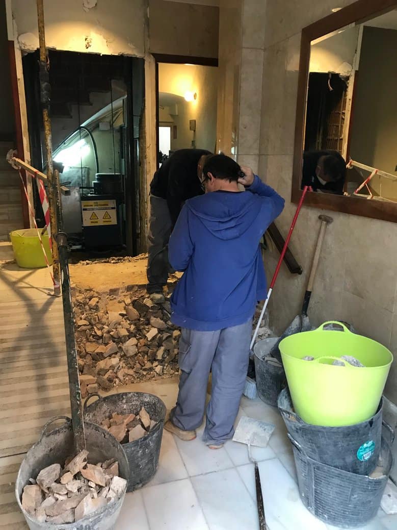 Worker standing among the rubble from renovating the elevator access.