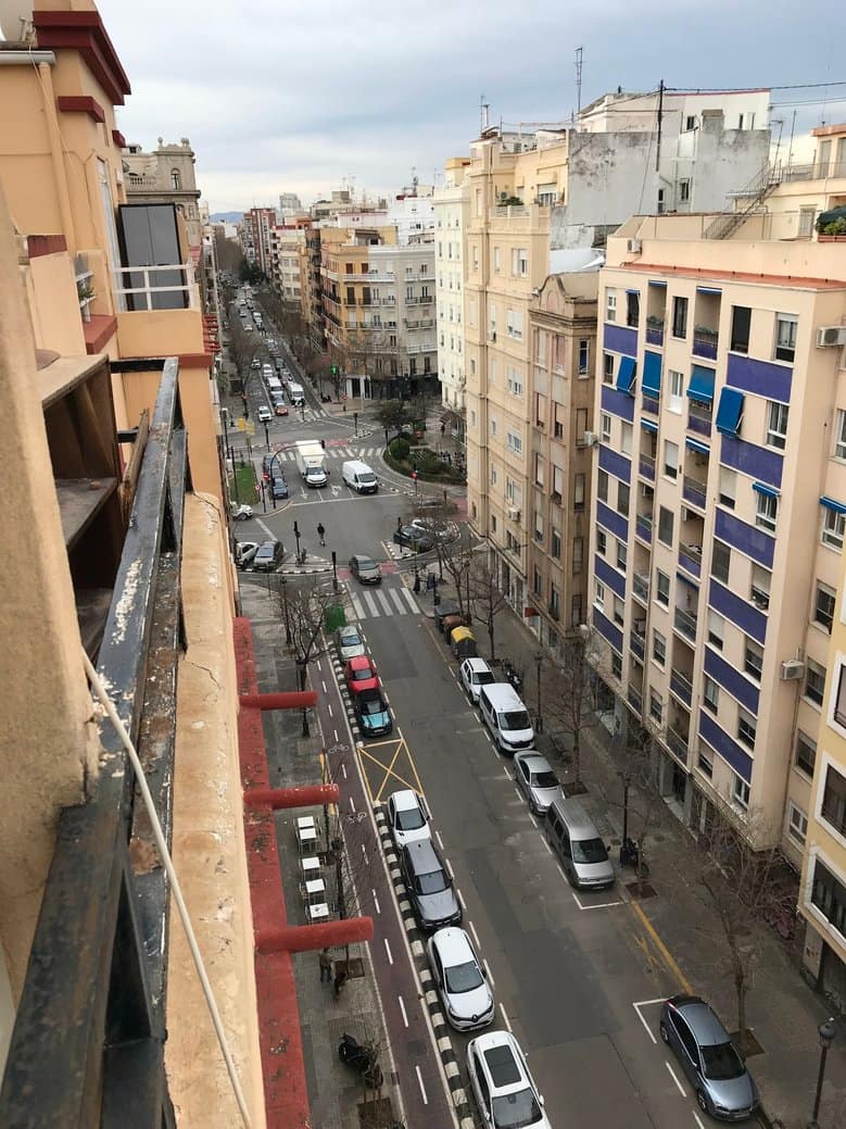 View of the street showing cars parked and an intersection in the distance.