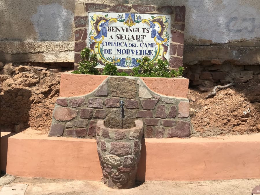 A simple water fountain dispenses water into a stone cistern.