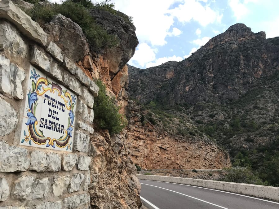 A sign naming the water fountain with mountains in the background.