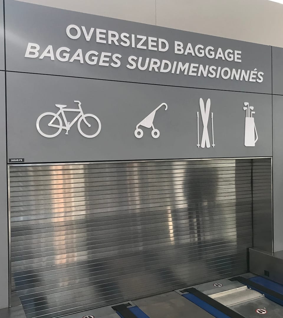 Over-sized baggage sign and pick-up point showing icons of bicycle, baby stroller, skil equipment, and golf clubs.