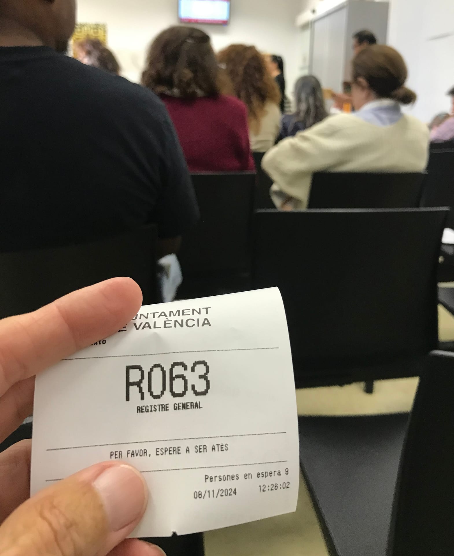 FIngers holding up a printed number for a waiting list.