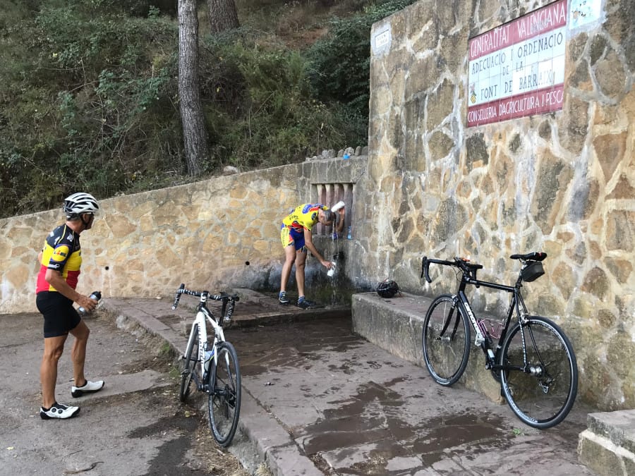 Cyclists fill water bottles and douse themselves from the water pipe.